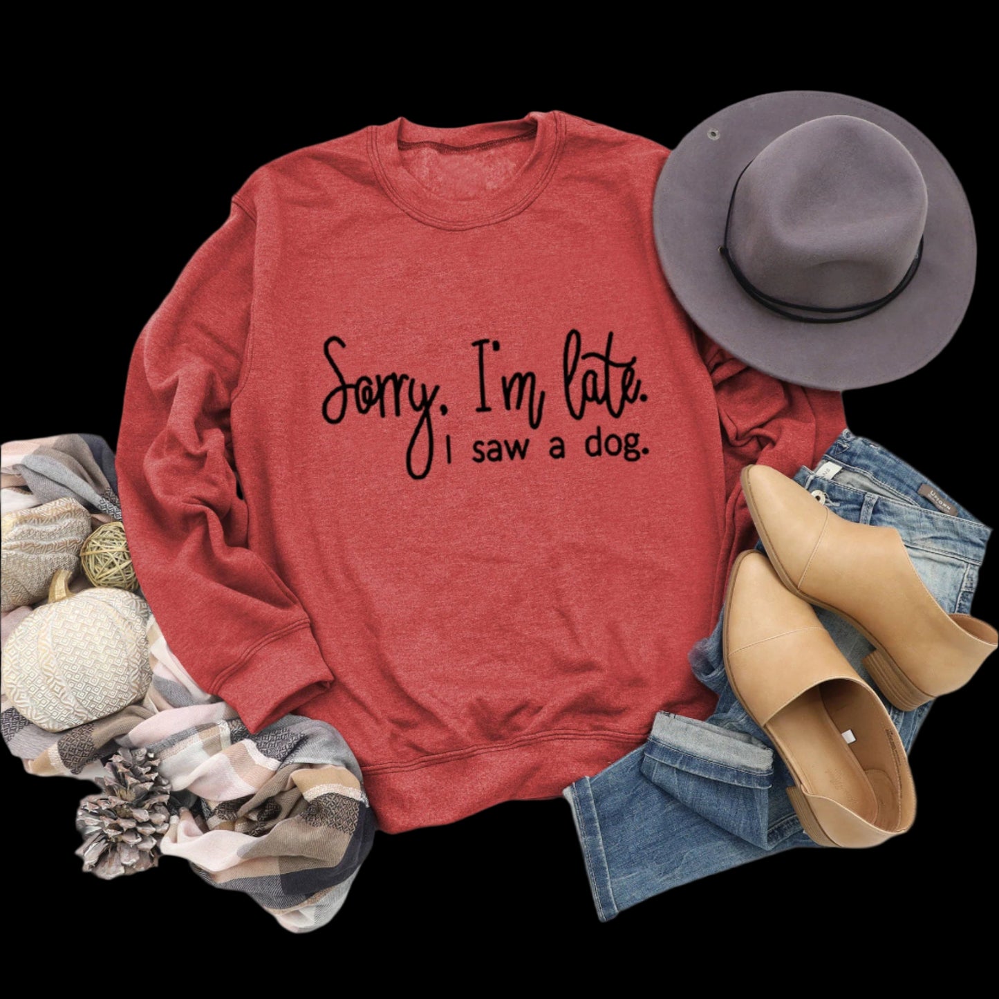 Red sweatshirt with text, hat, boots, and jeans on a wooden surface