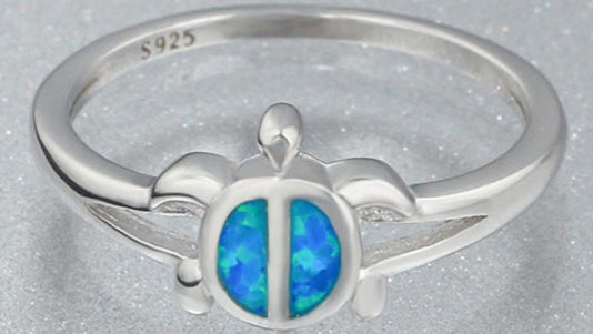 Silver ring with a blue opal stone on a gray background