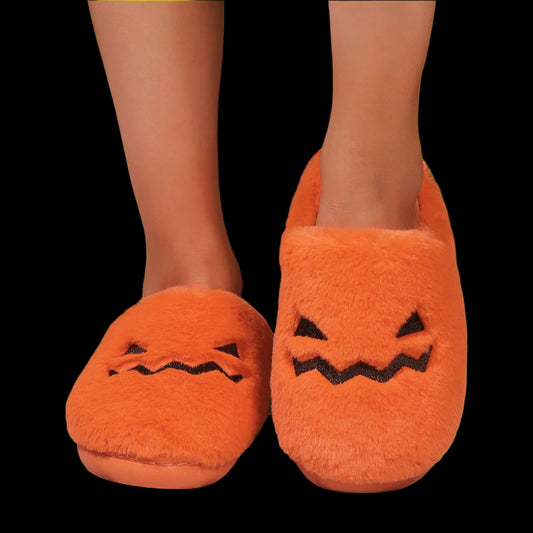 Orange pumpkin slippers with black facial features on a wooden floor.