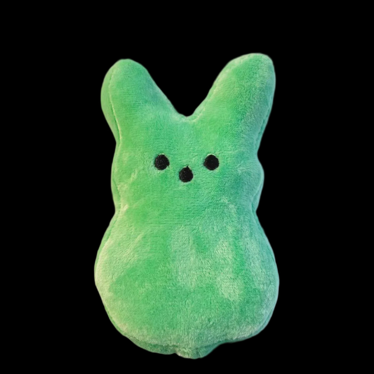 Green plush toy with black eyes on a light gray background