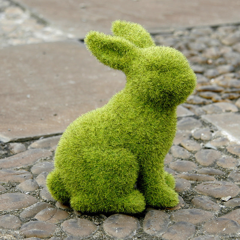Green moss rabbit sculpture on a stone pavement