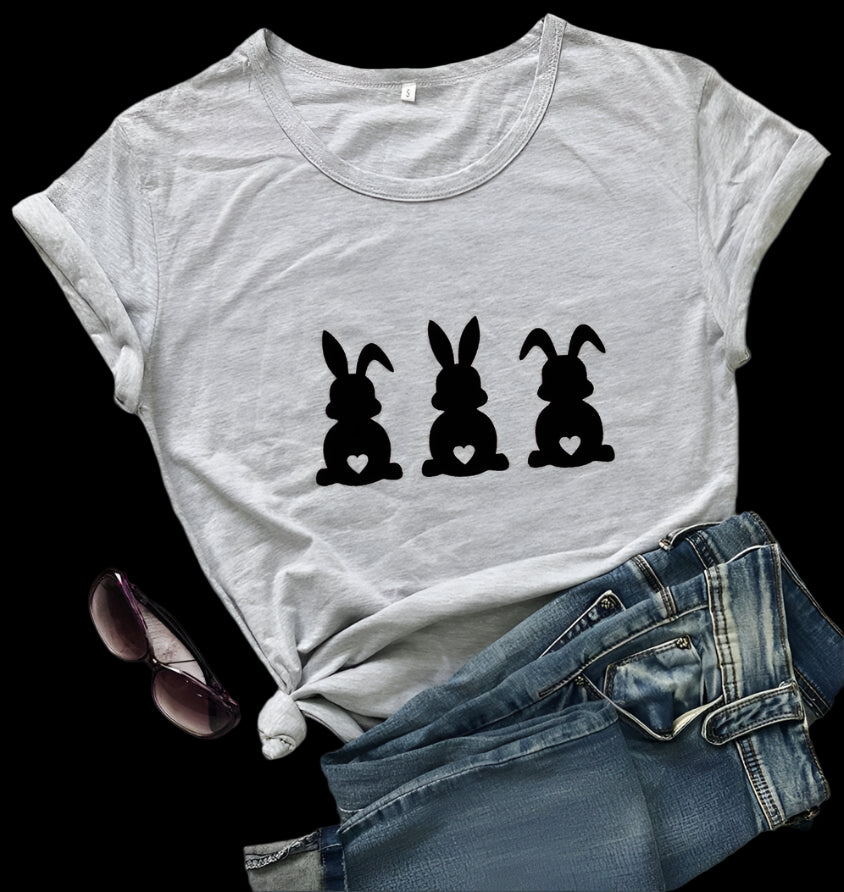 Gray t-shirt with black bunny silhouette design on a wooden surface with sunglasses and jeans.