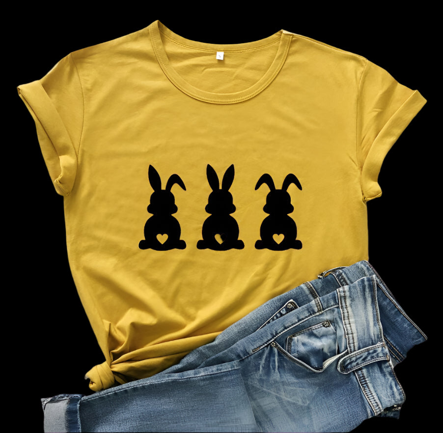 Yellow t-shirt with black rabbit illustrations on a wooden surface with jeans and berries.