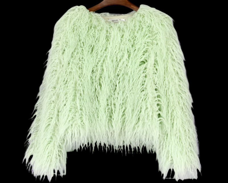 Light green feathered garment on a wooden hanger against a gray tiled wall.