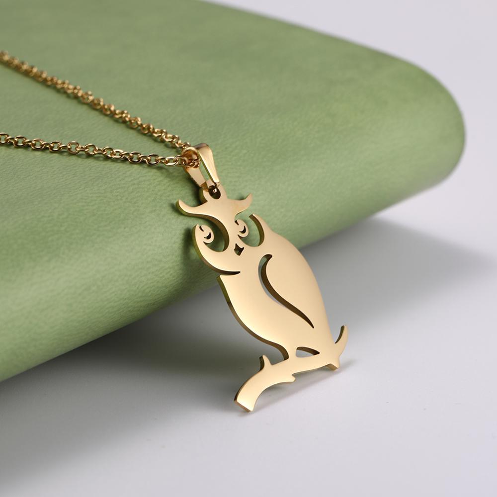 Gold owl-shaped pendant on a chain against a green fabric background