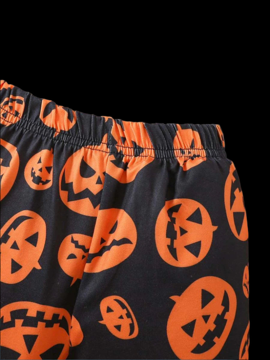 Black shorts with orange jack-o'-lantern patterns on a wooden surface