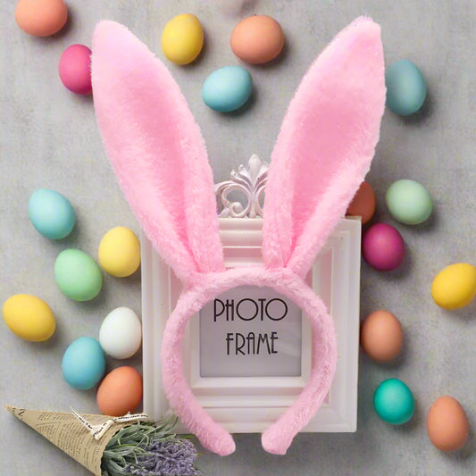 Pink bunny ears on a white background with a small photo frame and decorative elements.