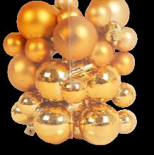 Clear box filled with gold Christmas ornaments on a white background