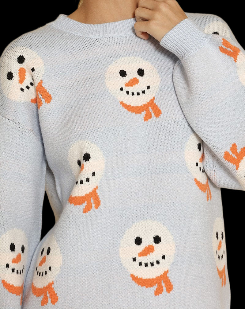 Light blue sweater with snowman patterns worn by a person against a beige background