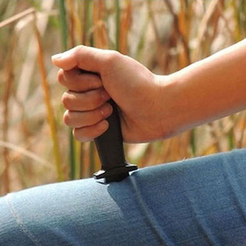 Hand holding a black object against a blurred natural background