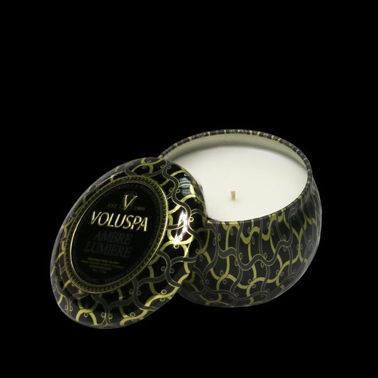 Voluspa candle in a decorative black and gold container on a white background