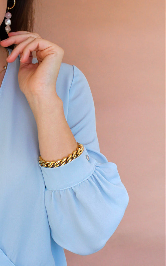 Woman wearing a light blue blouse and jeans against a beige background