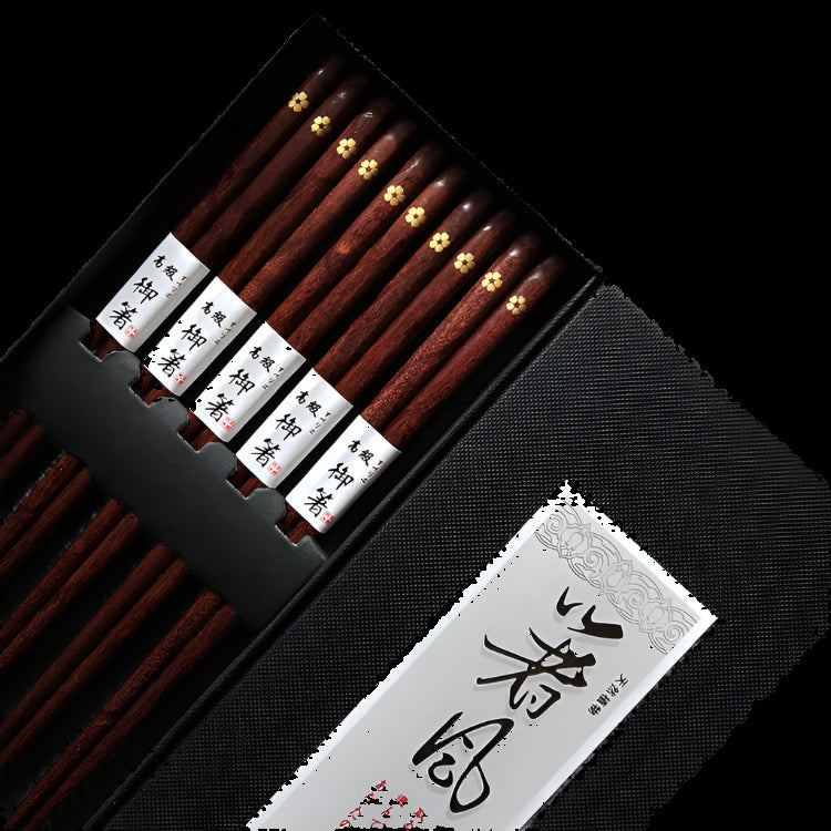 Set of wooden chopsticks in a black box with a decorative label on a textured background