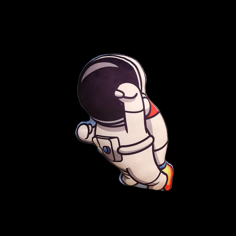 Cushion shaped like an astronaut on a couch with a plant and wooden shelf in the background
