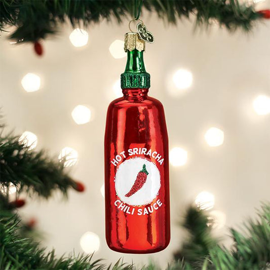 Red Hot Sriracha chili sauce bottle ornament on a Christmas tree with lights in the background