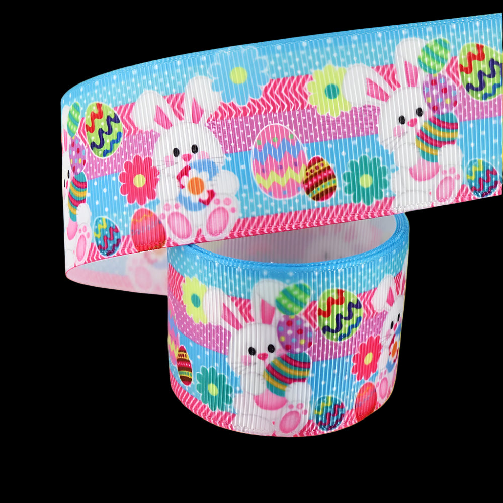 Two rolls of Easter-themed ribbon with bunnies and eggs on a white background