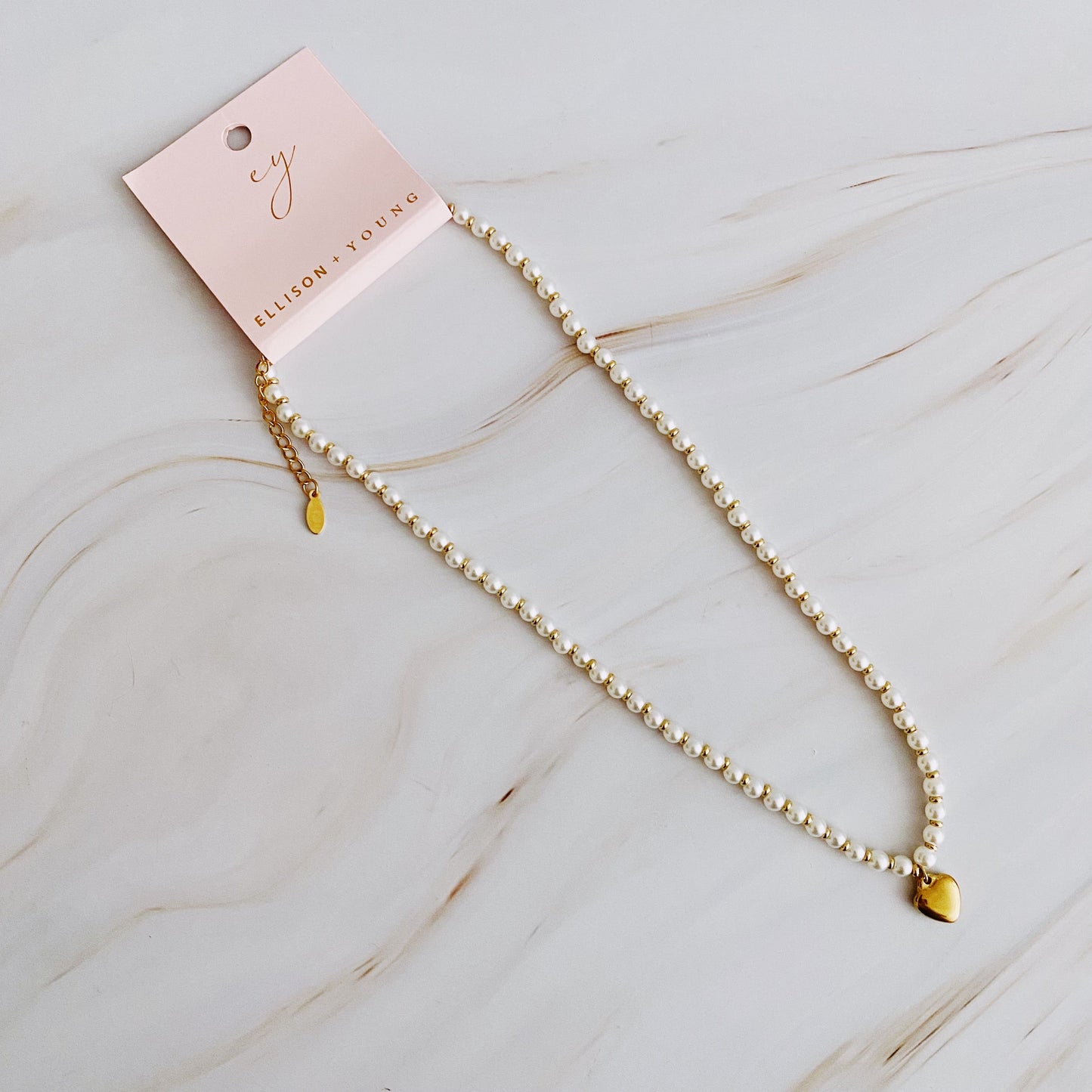 Pearl necklace with a heart charm on a marble surface