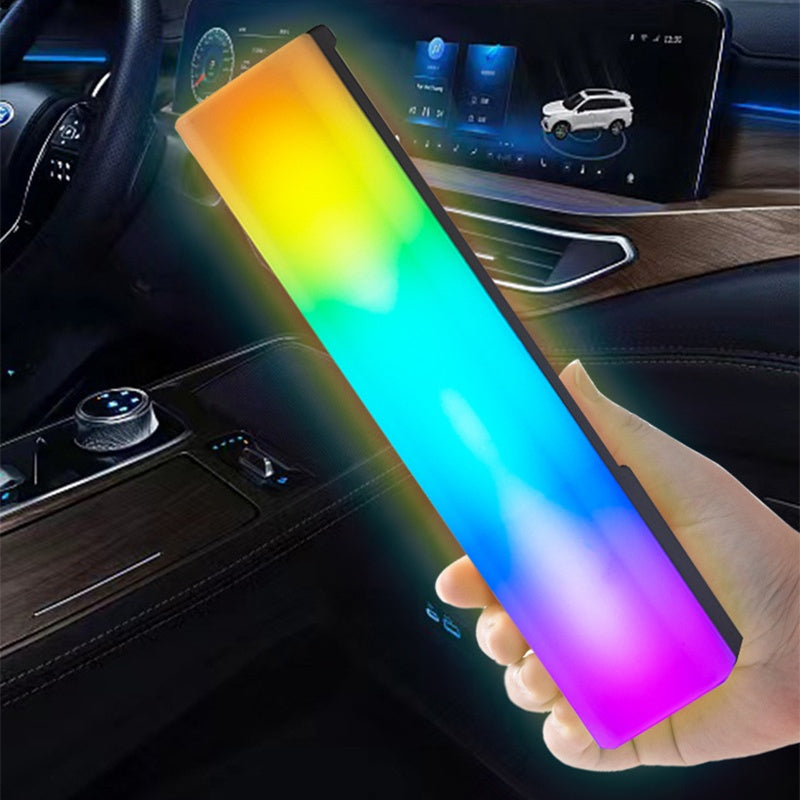 Hand holding a colorful light bar inside a car with a dashboard in the background