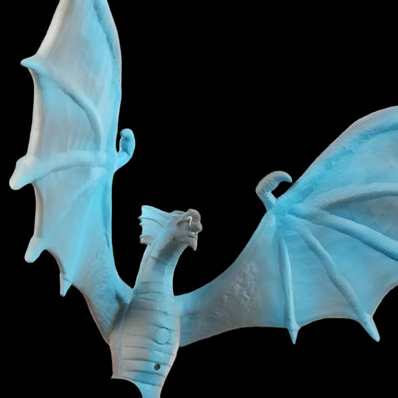 Blue dragon toy held by a hand against a white background
