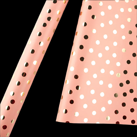 Pink paper with gold and black polka dots on a white background