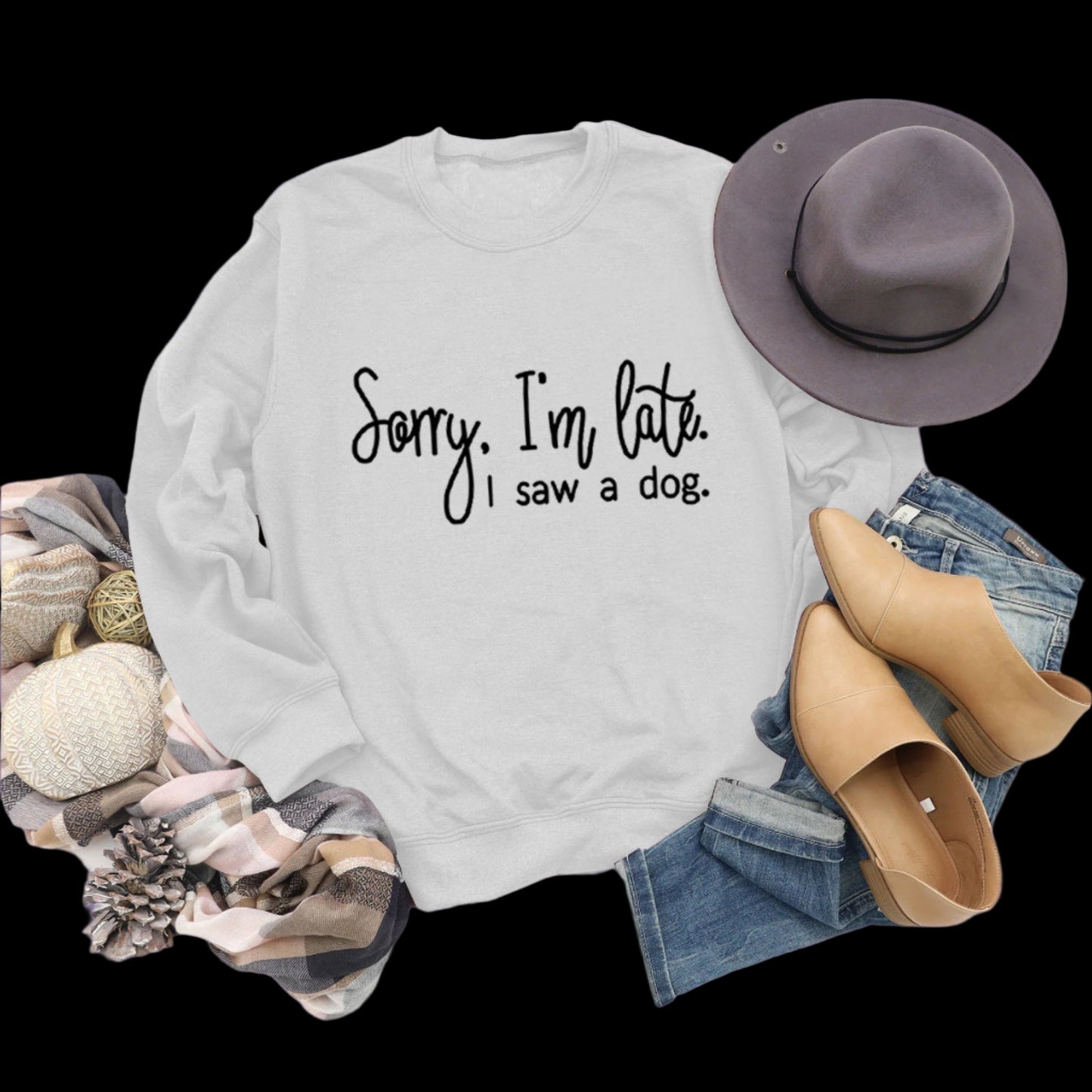 Gray sweatshirt with text, hat, boots, and jeans on a wooden surface