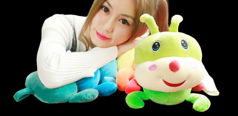 Woman holding a colorful caterpillar plush toy on a wooden table.