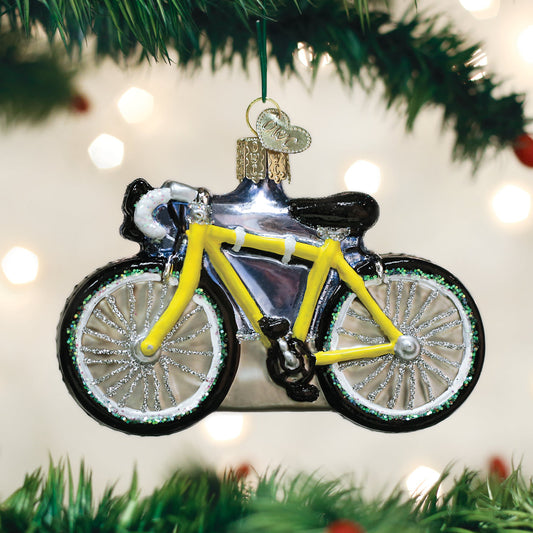 Bicycle ornament hanging on a Christmas tree with lights in the background