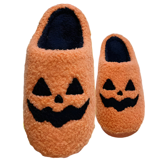 Pair of orange slippers with jack-o'-lantern faces on a white blanket.
