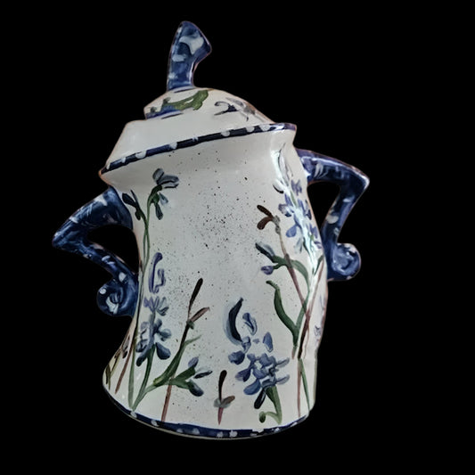 Ceramic jar with floral design and blue accents on an orange background