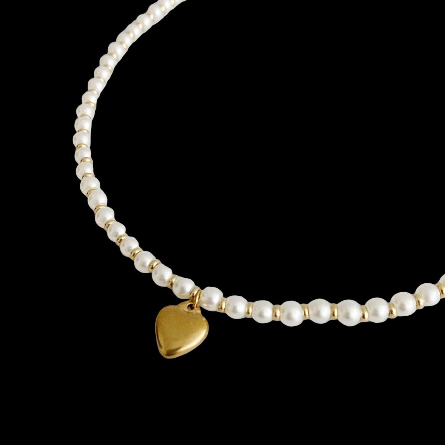 Pearl necklace with a gold heart pendant on a light gray background