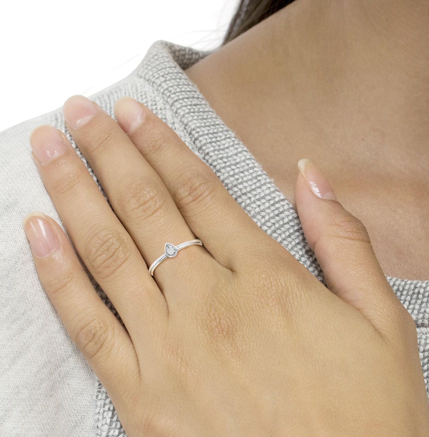 Close-up of a hand wearing a silver ring on a neutral background