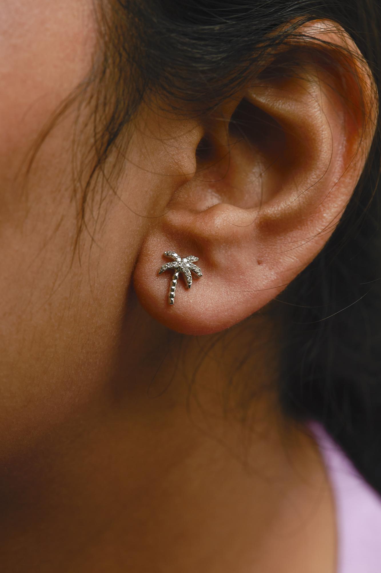 Close-up of an ear wearing a silver palm tree earring.