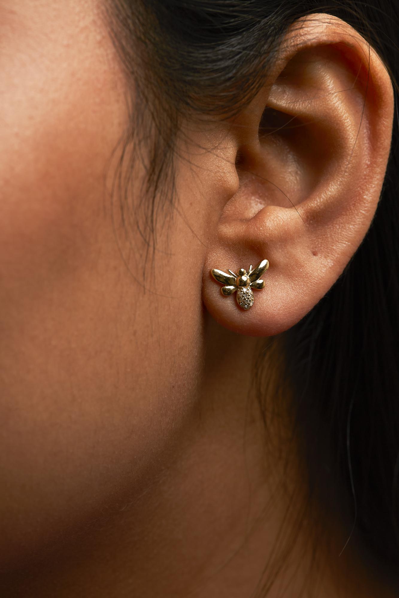 Close-up of an ear wearing a gold earring with a detailed design.