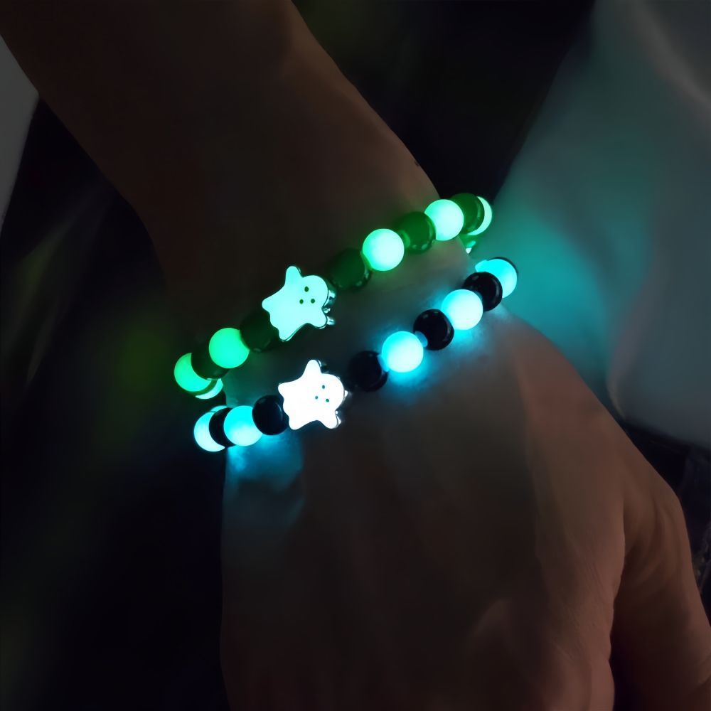 Glowing bracelets with star-shaped beads on a wrist against a dark background