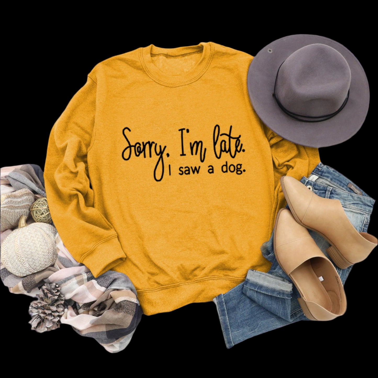 Yellow sweatshirt with text, hat, shoes, and jeans on a wooden surface