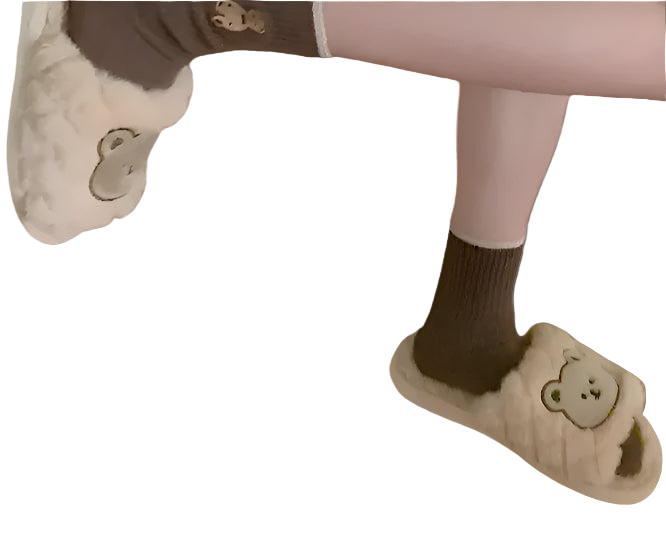 Person wearing a fluffy bear-shaped bag and matching slippers in a room with floral wallpaper.