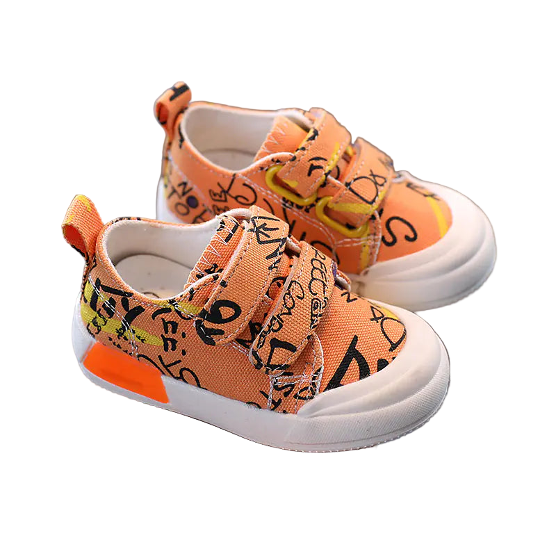 Orange children's sneakers with black and yellow patterns held in a hand against a gray background