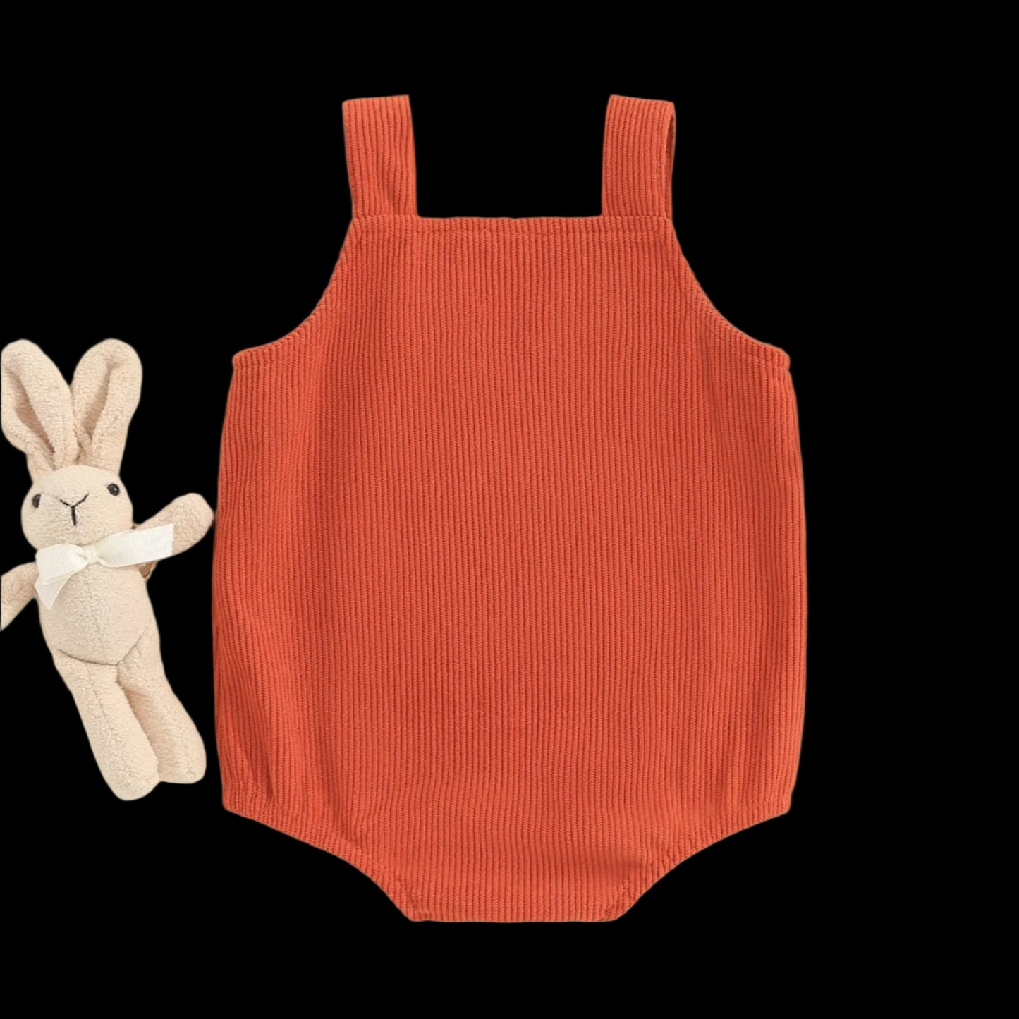 Orange ribbed romper on a beige background with a plush toy and decorative elements.