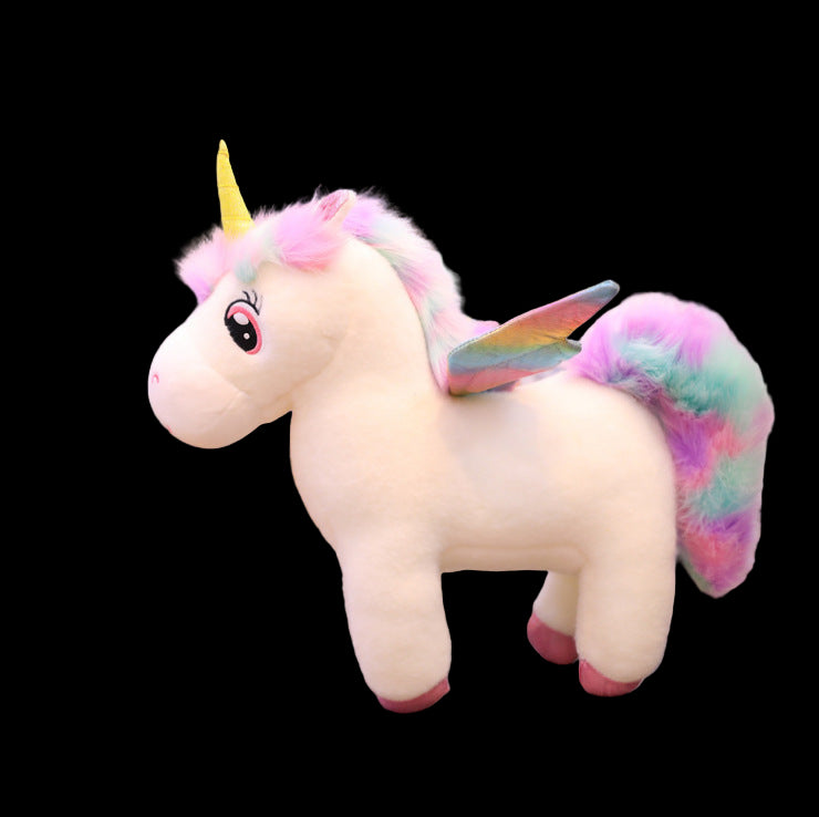 Stuffed unicorn toy with rainbow wings on a wooden floor