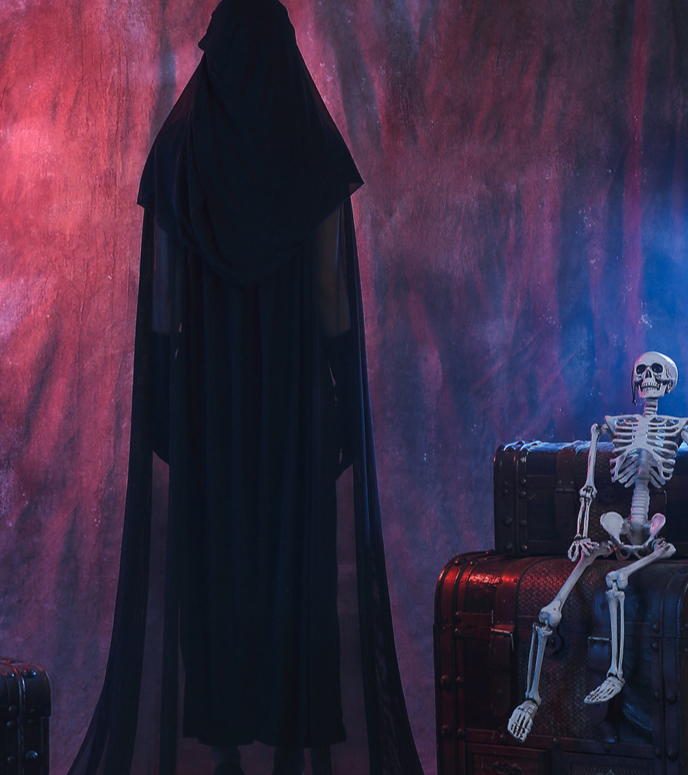 Person in a dark hooded cloak facing a skeleton on a chest against a mystical background