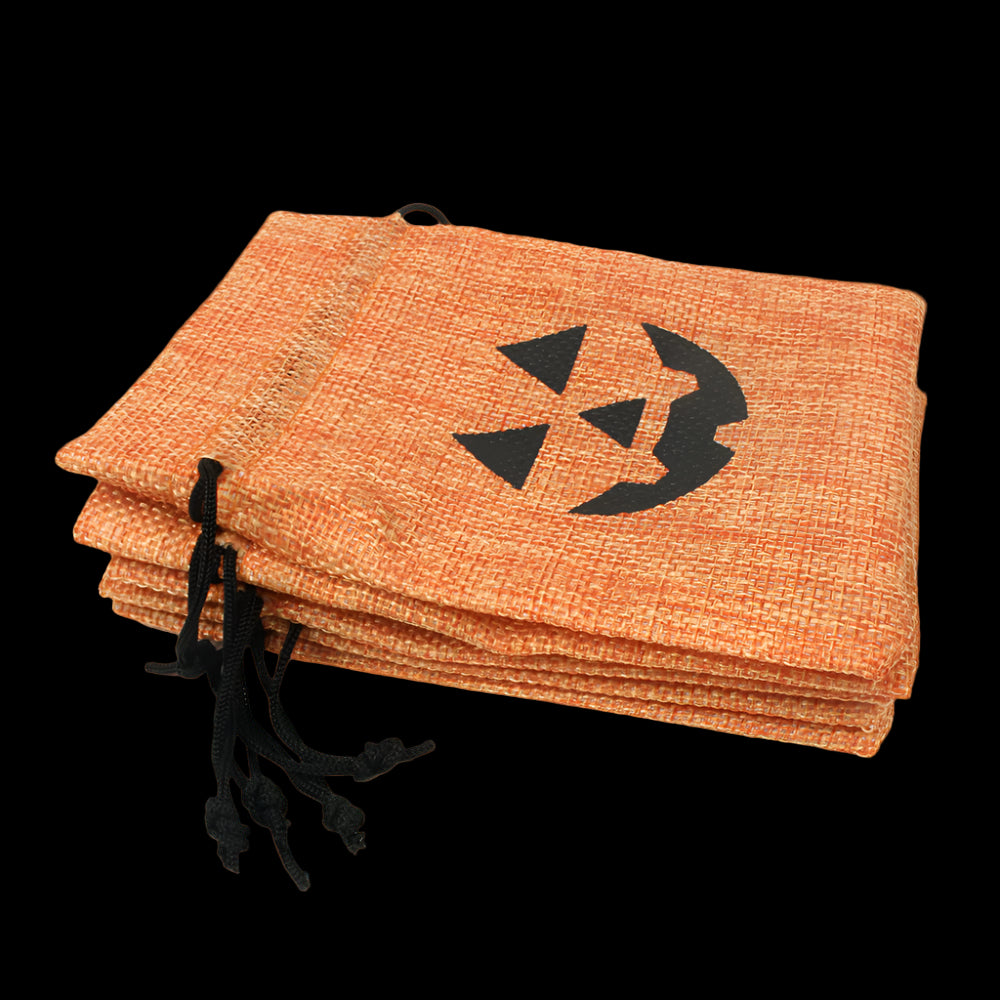 Stack of orange drawstring bags with black pumpkin face design on a white background