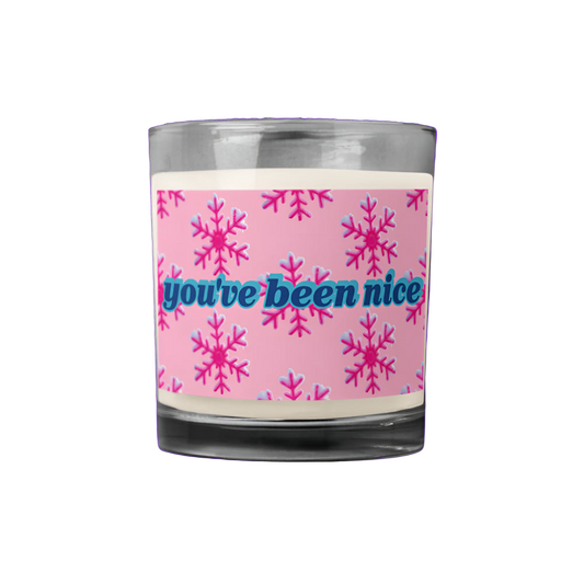 Candle with pink snowflake design and 'you've been nice' text on a white background