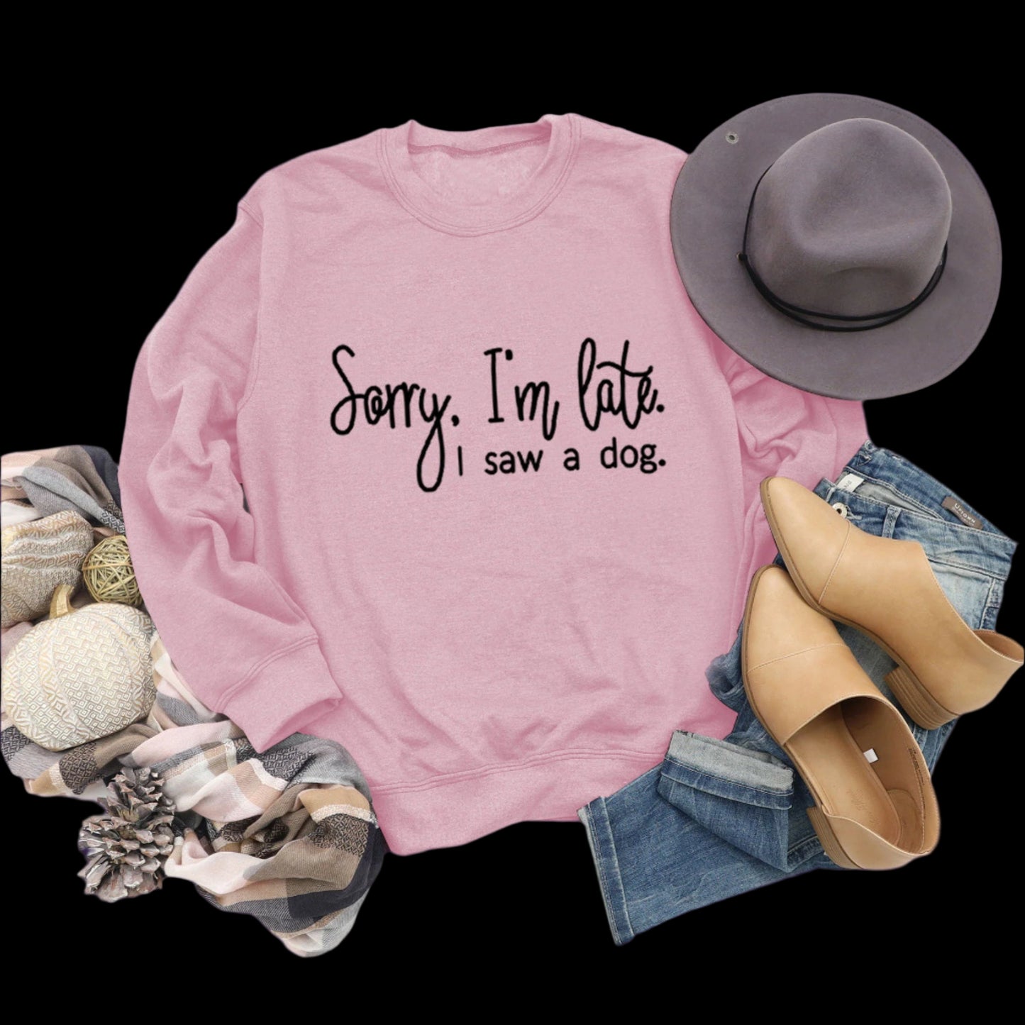 Pink sweatshirt with text, hat, shoes, and accessories on a wooden surface