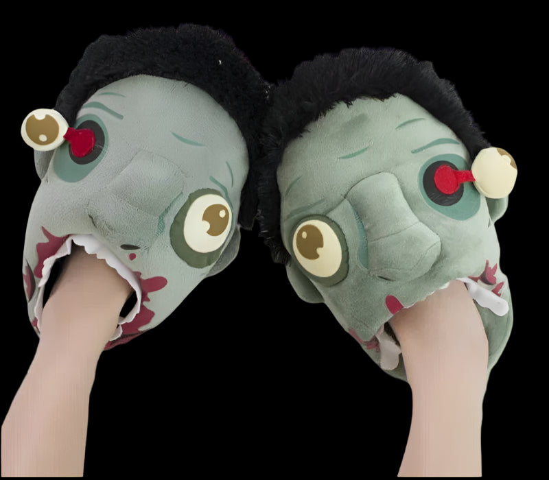 Pair of cartoonish green slippers with black hair and red eyes on a white background.