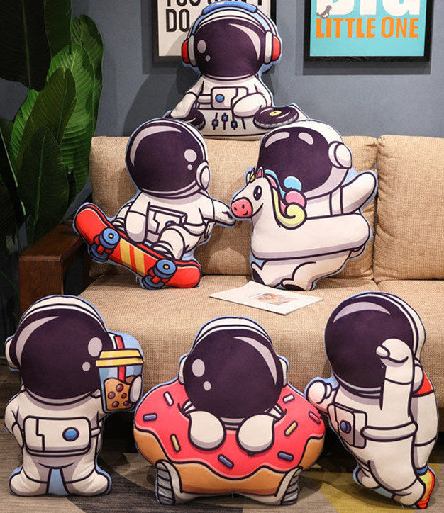 Cute plush toys shaped like astronauts and a donut on a couch in a living room setting.