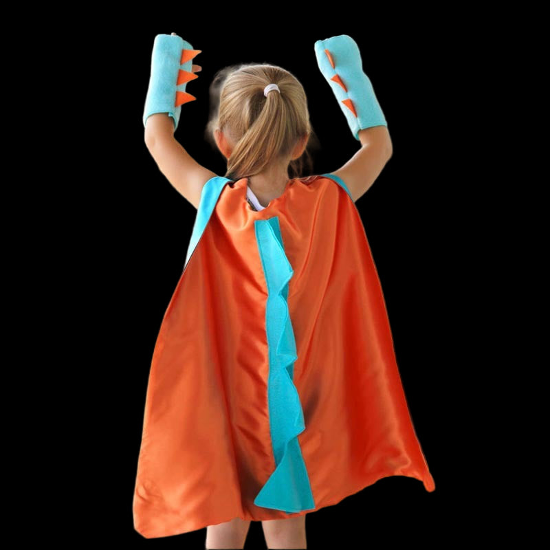 Child wearing an orange superhero cape with blue trim and matching gloves outdoors.