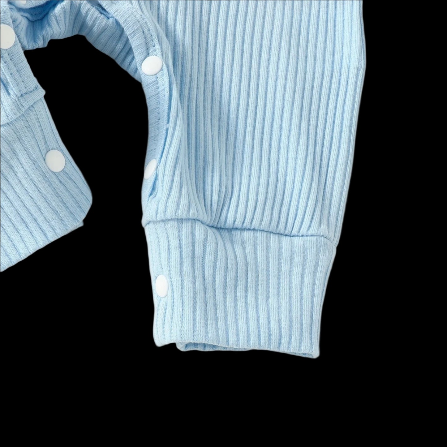 Light blue ribbed sweater with white buttons on a beige background