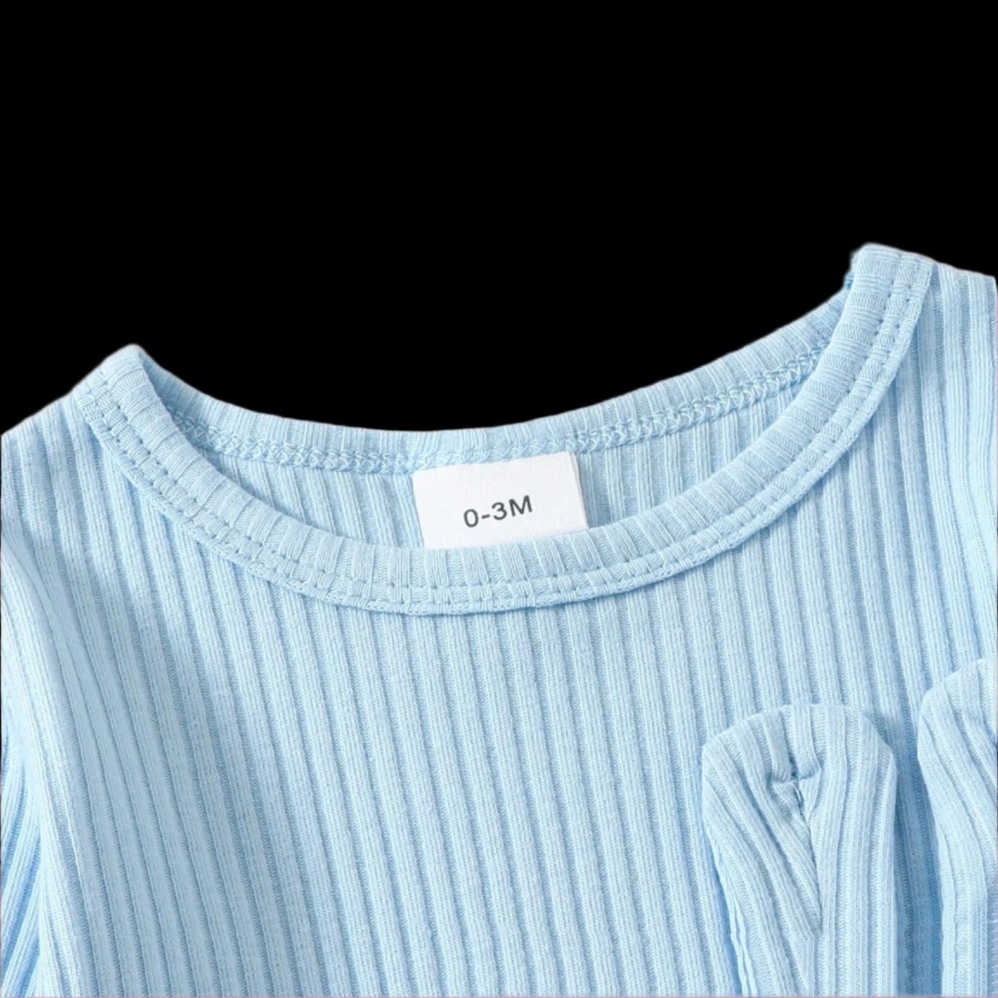 Close-up of a light blue ribbed sweater with a size label on a beige background