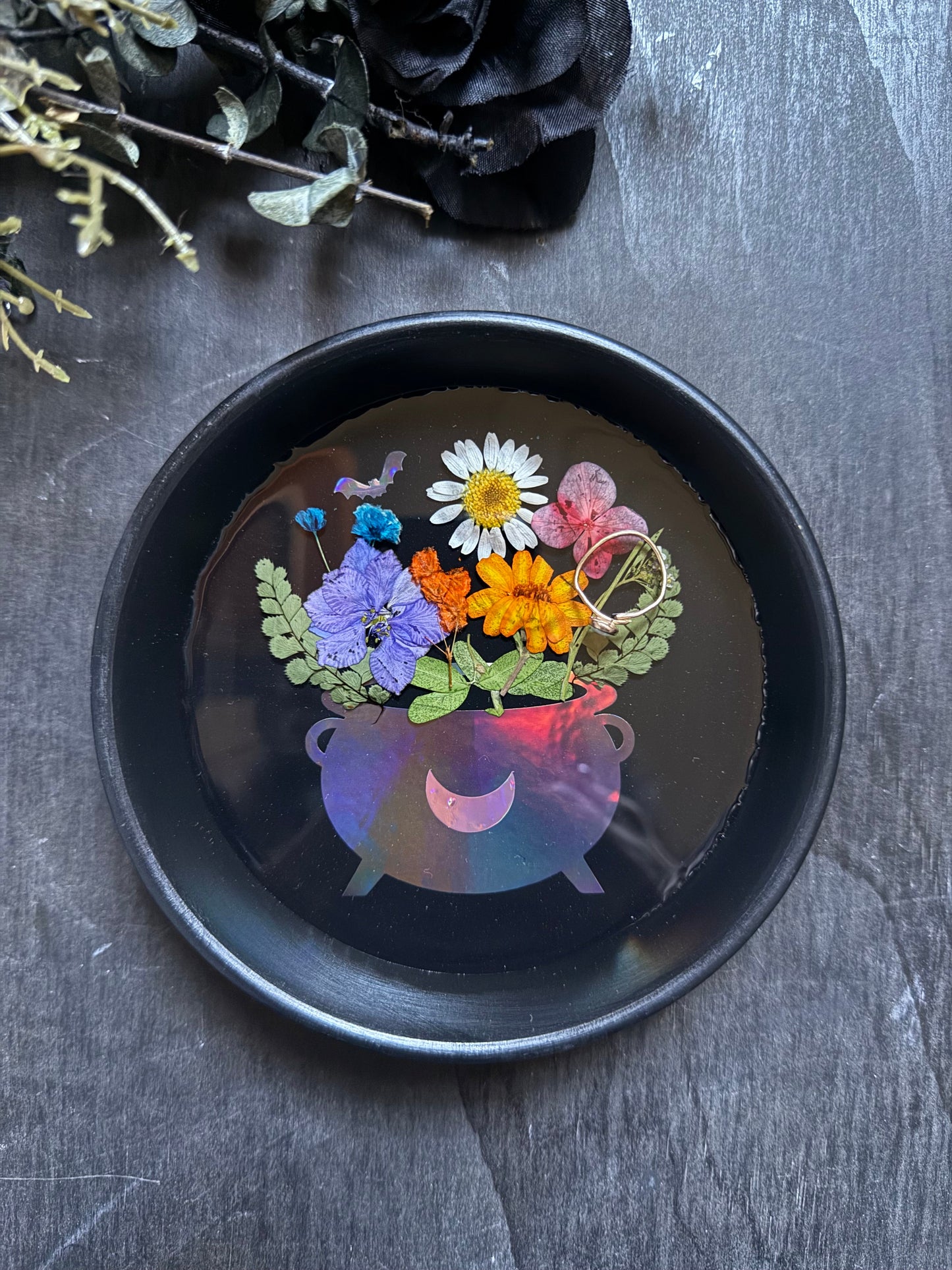 Decorative black dish with colorful floral design on a dark surface