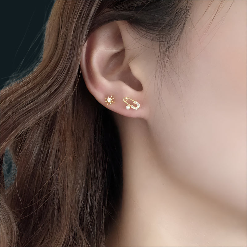 Close-up of an ear wearing gold earrings with a star and heart design.